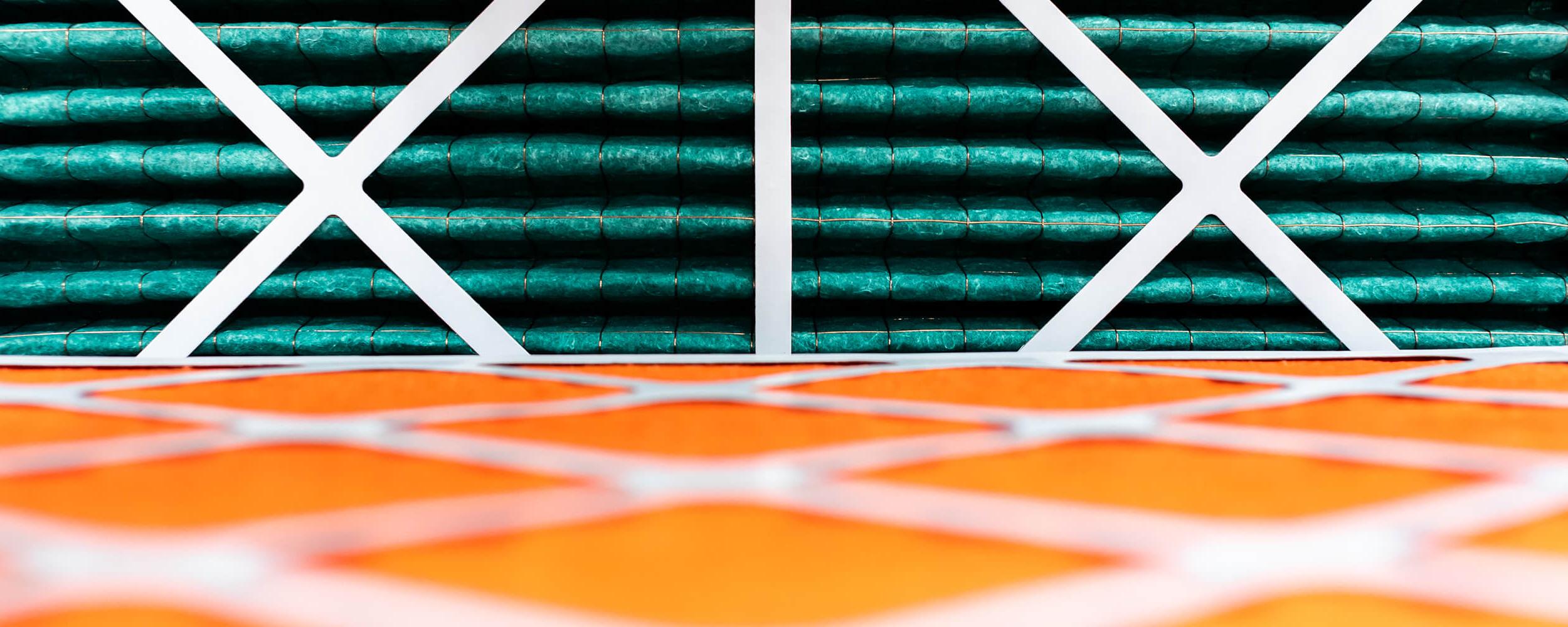 特写照片的卷橙色和绿色绝缘材料被举行到位与白色的交叉框架